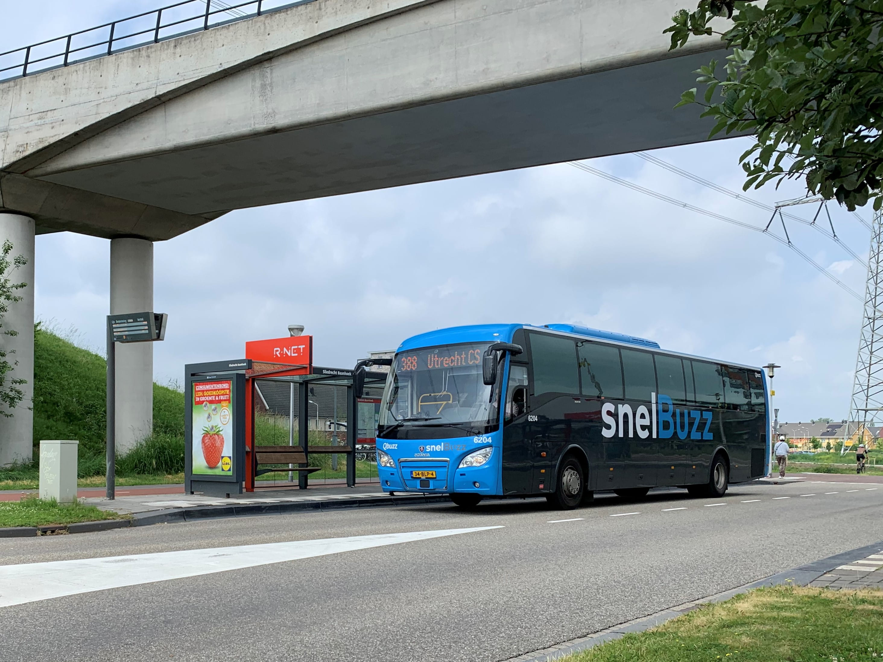Een SnelBuzz staat bij een bushalte onder een viaduct